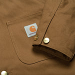 Carhartt WIP Michigan Coat Hamilton Brown/Tobacco Rigid. Foto de detalhe do punho e do bolso no peito.